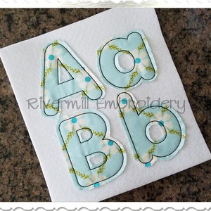 Peut inclure: Quatre lettres en feutre, A, a, B et b, de couleur bleu clair avec un motif floral blanc. Les lettres sont soulignées de fil noir.