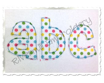 May include: Three felt letters, "a", "b", and "c", on a white background with yellow, green, blue, and pink polka dots. The letters are outlined in blue thread.
