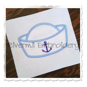 Puede incluir: Sombrero de marinero azul bordado con un ancla en el centro. El ancla es de color morado.