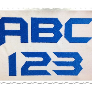 May include: Blue embroidered letters "ABC 123" on a white background.