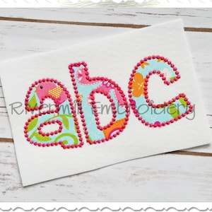 Könnte beinhalten: Gestickte Buchstaben "abc" in einem farbenfrohen Patchwork-Stil mit rosa Nähten. Die Buchstaben sind mit rosa umrandet und mit verschiedenen floralen und tierischen Mustern gefüllt.