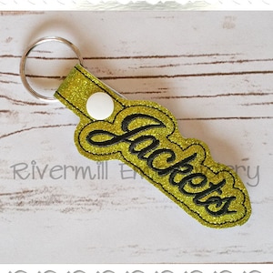 May include: A gold glitter keychain with a black embroidered word "Jackets".