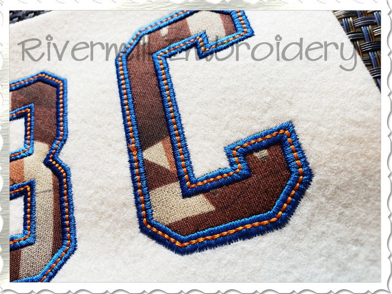 Puede incluir: Dos letras bordadas, "3" y "C", en un patr&oacute;n de camuflaje marr&oacute;n y blanco con costuras azules. Las letras est&aacute;n sobre un fondo blanco.