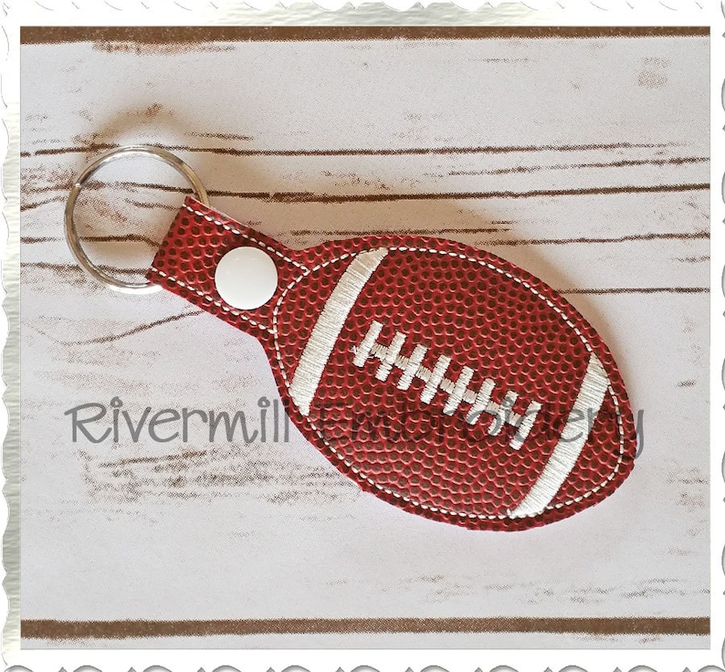 Puede incluir: Llavero con forma de bal&oacute;n de f&uacute;tbol rojo y blanco con un dise&ntilde;o cosido blanco y un anillo de llave plateado.