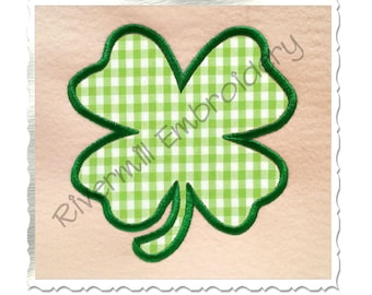 May include: Green four-leaf clover with a gingham pattern inside and a green outline. The clover is on a light pink background. Rivermill Embroidery is written in the bottom left corner.