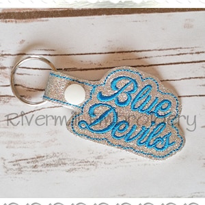 May include: A silver glitter keychain with a blue embroidered cloud shape that says "Blue Devils".
