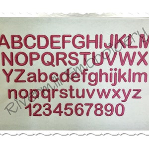 May include: A white background with a pink embroidered alphabet and numbers. The letters are uppercase and lowercase, and the numbers are 1 through 9.