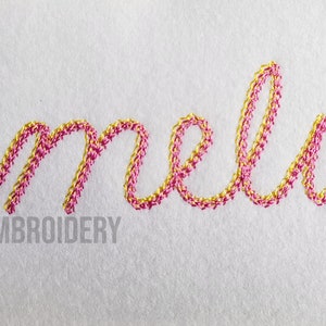 Pu&ograve; includere: Nome ricamato "Amelia" in filo rosa e oro su uno sfondo di tessuto bianco. Il testo "Rivermill Embroidery" &egrave; visibile sotto il nome.