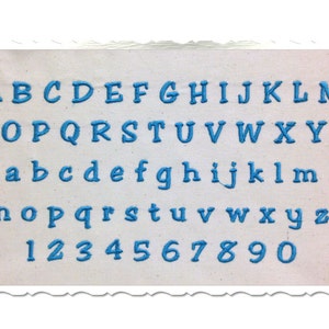 Puede incluir: Una tela blanca con un alfabeto y números bordados en azul. El alfabeto incluye letras mayúsculas y minúsculas y los números del 1 al 9 y el 0.