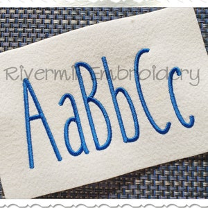 May include: A close-up of a white fabric with the letters A, a, b, b, and c embroidered in blue thread. The text "Rivermill Embroidery" is visible in the background.