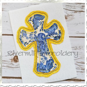 May include: A blue and white floral cross with a yellow outline. The cross is on a white background.