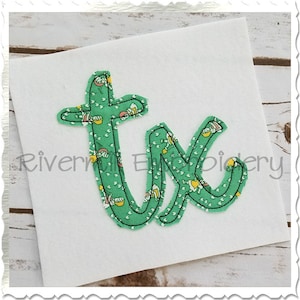 May include: Green fabric letters "tk" with a white background and a floral pattern. The letters are stitched together and have a slightly raised appearance.