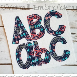 May include: Embroidered letters A, B, and C in uppercase and lowercase. The letters are outlined in navy blue and filled with a geometric pattern in shades of pink, blue, and gray.