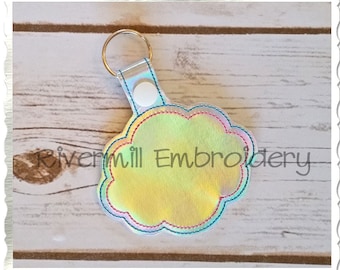 May include: A white iridescent key chain with a cloud-shaped tag. The tag has a rainbow iridescent finish and a blue, red, and green stitched border.