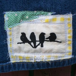 May include: A denim patch with a white background and a black silhouette of four birds. The patch is decorated with green and yellow checkered fabric.