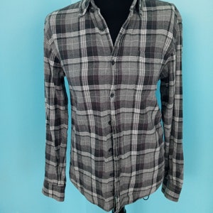 May include: A gray and white plaid long-sleeve button-up shirt.