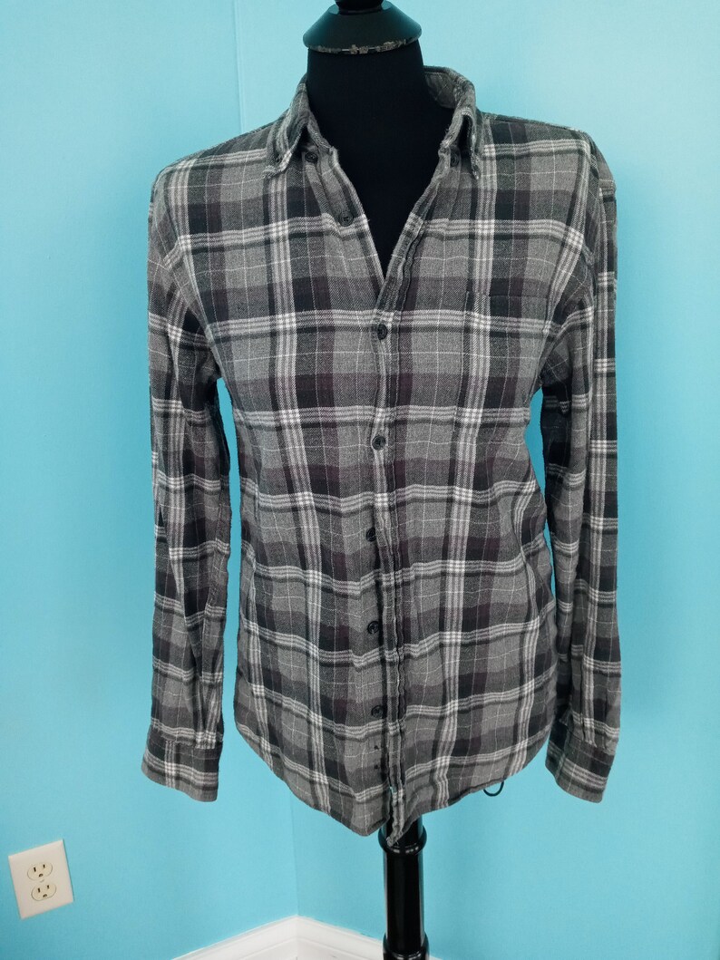 May include: A gray and white plaid long-sleeve button-up shirt.