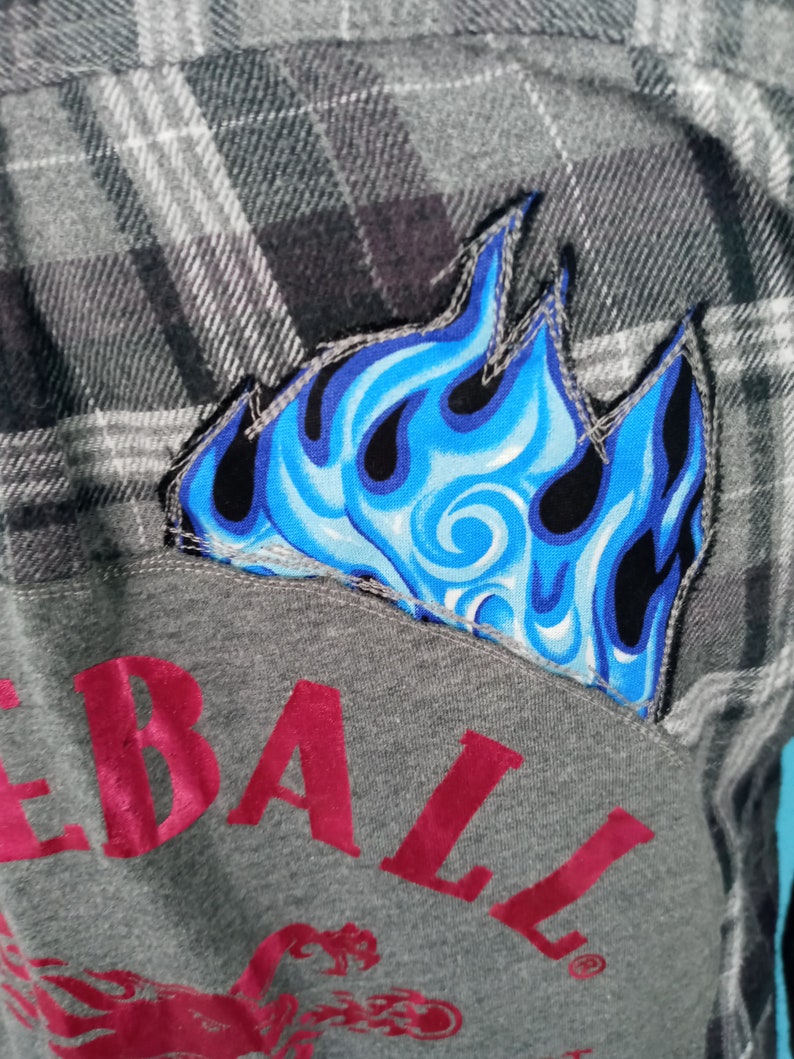 May include: A gray flannel shirt with a blue flame patch and a red "Rebel" logo on the front.