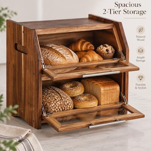 May include: A two-tier wooden bread box with clear glass drop-down doors and silver metal handles. The interior holds a loaf of sourdough, croissants, a muffin, bagels, and sliced bread. Text on the image reads Spacious 2-Tier Storage.