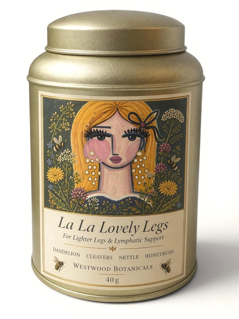 May include: A gold-colored metal tin with a lid, featuring a label with the text "La La Lovely Legs." The label includes an illustration of a woman with blonde hair and floral elements. The tin contains 40 grams of product.