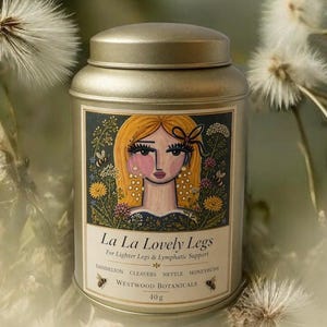 May include: A gold-colored metal tin with a lid, featuring a label with the text "La La Lovely Legs" and an illustration of a woman with blonde hair. The label also lists ingredients and the weight of the product, 40g.