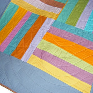May include: A colorful quilt with a patchwork design featuring stripes and curves in shades of blue, green, yellow, orange, pink, and purple.