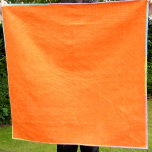 May include: A large orange quilt with a wavy quilted pattern. The quilt is made of a soft, textured fabric and has a light green border.