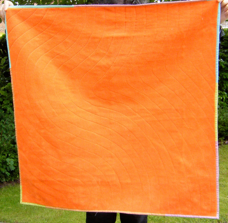 May include: A large orange quilt with a wavy quilted pattern. The quilt is made of a soft, textured fabric and has a light green border.