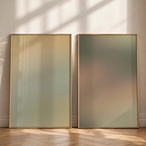 May include: Two rectangular wall art prints displayed in thin gold frames. The left print features a soft gradient transitioning from warm beige to muted sage green. The right print displays a smooth blend of olive green and soft brown tones.