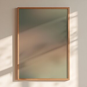 Könnte beinhalten: Ein rechteckiges Wandbild mit einem weichen, unscharfen Farbverlauf, der von einem gedämpften Salbeigrün oben zu einem warmen, erdigen Beigeton unten übergeht, eingefasst in einen schlichten Rahmen aus hellem Holz.