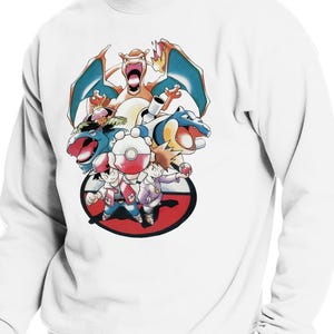 May include: White sweatshirt featuring a colorful graphic of various cartoon characters, including a large orange dragon with blue wings and several other creatures. The design is set against a red and white circular background.