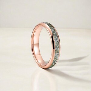 May include: Rose gold ring featuring a band of grey and silver stones. The ring has a simple band design with a polished finish. The ring is displayed on a white background.