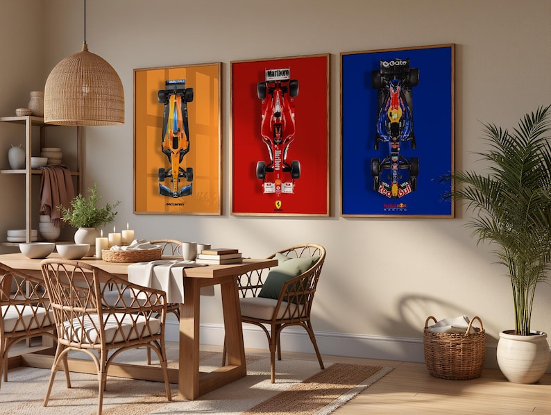 May include: Three framed Formula 1 car prints. The prints feature top-down views of race cars against orange, red, and blue backgrounds. The room has a wooden dining table, wicker chairs, and a woven pendant light.