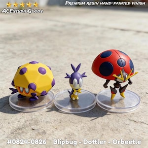 Puede incluir: Tres figuras de resina pintadas a mano de Blipbug, Dottler y Orbeetle sobre bases transparentes. El Blipbug es amarillo con lunares morados, el Dottler es morado y amarillo, y el Orbeetle es rojo con lunares negros. El texto "ACESTUDIO GOODS" y "PREMIUM RESIN HAND-PAINTED FINISH" son visibles.