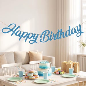 May include: A blue glittery Happy Birthday banner hanging on a string. The letters are in a cursive script font and feature a sparkling texture. The banner is suspended horizontally, displaying the words Happy Birthday in a bright blue color.