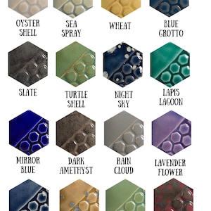 May include: A grid of sixteen hexagonal ceramic glaze samples, each featuring a smooth section and a textured honeycomb pattern. Colors include Oyster Shell, Sea Spray, Wheat, Blue Grotto, Slate, Turtle Shell, Night Sky, Lapis Lagoon, Mirror Blue, Dark Amethyst, Rain Cloud, Lavender Flower, Demin Blue, Gold Mine, Tidal Pool, and Volcanic Glow.