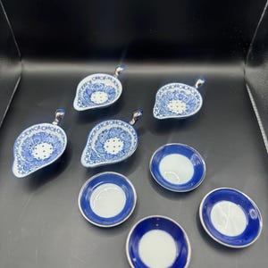 May include: A collection of blue and white porcelain serving pieces. The set includes leaf-shaped dishes with handles and small round plates, all with intricate floral patterns and a blue rim.