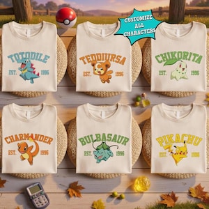 Puede incluir: Seis camisetas color crema con varios personajes de dibujos animados y texto. Cada camiseta muestra un nombre de personaje diferente, la palabra "EST." y el año "1996". También se ve una Pokeball y el texto "CUSTOMIZE ALL CHARACTERS".