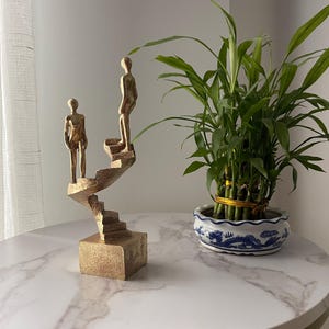 Golden sculpture “Evolution” – Modern statue on a spiral staircase – Luxury decoration – Contemporary art