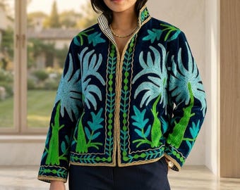 Puede incluir: Chaqueta azul marino con intrincados bordados en tonos verdes y azules. La chaqueta presenta un cuello alto y un ribete dorado en los bordes. El diseño incluye patrones florales y de hojas estilizados, creando un aspecto único y artístico.