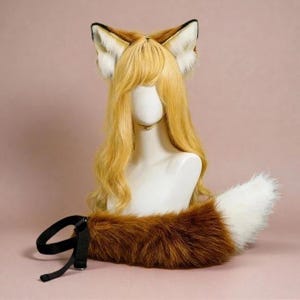 May include: A cosplay fox kit, featuring a set of ears, a wig, and a tail. The ears are brown and white, the wig is blonde, and the tail is brown with a white tip. The tail has a black strap for attachment.