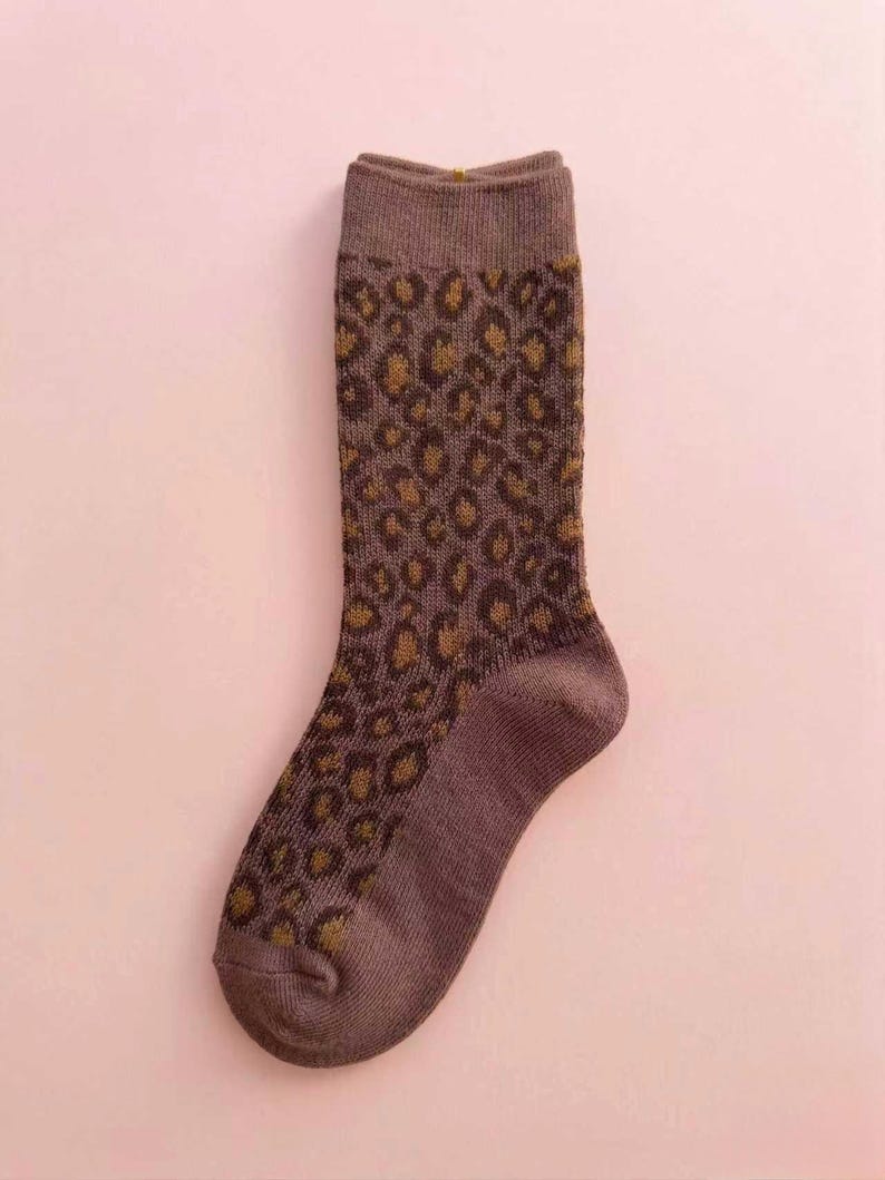 K&ouml;nnte beinhalten: Ein Set aus drei Keramikbechern mit cremefarbener, gesprenkelter Glasur. Jeder Becher hat ein handgemaltes Blumendesign in Blau-, Gr&uuml;n- und Gelbt&ouml;nen. Die Becher haben eine schlichte, moderne Form.