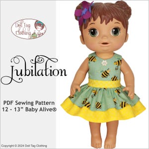 May include: PDF sewing pattern for a 12-13 inch Baby Alive doll. The pattern is called "Jubilation" and features a green dress with a yellow bottom and a bee print. The doll is wearing the dress and has brown hair and brown eyes.