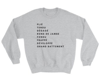 May include: A gray sweatshirt with black text listing ballet terms in French: Plié, Tendu, Dégagé, Rond de Jambe, Fondu, Frappé, Développé, Grand Battement.