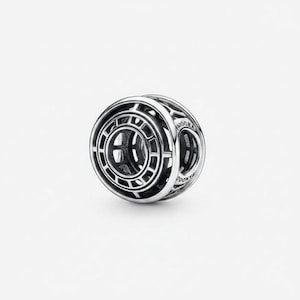 Puede incluir: Un charm de plata con un diseño geométrico. El charm es esférico con cortes rectangulares y circulares. La palabra "PANDORA" es visible en el lateral. Diseñado para ser usado con una pulsera o collar.