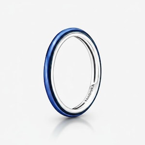 May include: A silver ring with a vibrant blue enamel band. The ring has a sleek, minimalist design and the brand name "PANDORA" is visible on the inside of the band. This piece of jewelry is perfect for everyday wear.