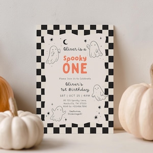 Puede incluir: Una tarjeta de invitación rectangular con un borde de cuadros blancos y negros. El centro tiene un fondo crema con dibujos lineales negros de fantasmas, estrellas y una luna creciente. El texto dice: Oliver is a Spooky ONE, Please Join Us to Celebrate Oliver's 1st Birthday, SAT | OCT 25 | 4PM, At 123 Spooky Lane, Nashville, TN 37203, RSVP to: +123.456.7890, Costumes Encouraged!