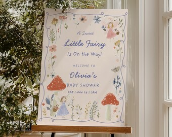 May include: A baby shower sign with the text "A Sweet Little Fairy Is On the Way!" and "Welcome to Olivia's BABY SHOWER." The sign features illustrations of fairies, mushrooms, and flowers, with a light blue border and text.