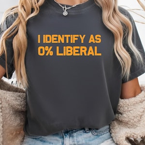May include: Dark grey t-shirt with the orange text "I IDENTIFY AS 0% LIBERAL". The t-shirt has a crew neck and is made of a soft material. A casual wear item.