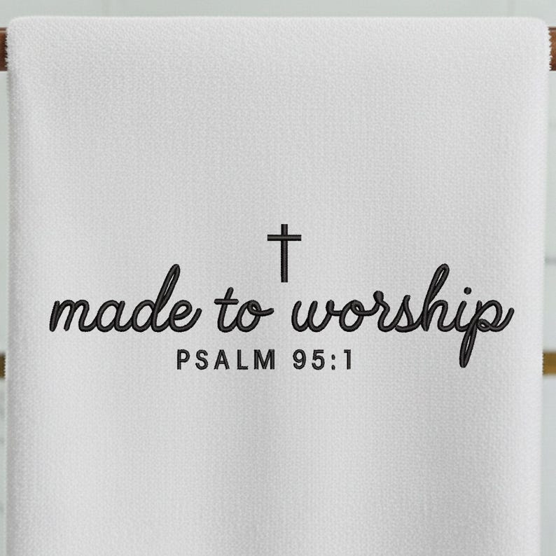 May include: White towel with the words "made to worship" in a script font, a cross, and the text "PSALM 95:1" in a simple font. The towel is hanging on a wooden rod.